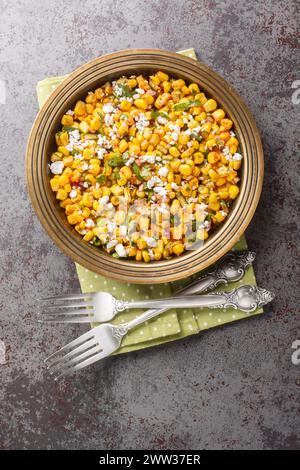 Hausgemachter mexikanischer Street Corn Esquites Salat mit Jalapeno, Koriander, Cotija-Käse, Zwiebeln und Gewürzen, gewürzt mit Sauerrahm in Nahaufnahme auf dem Teller Stockfoto