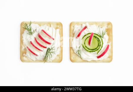 Zwei quadratische Creme Cracker mit Frischkäse, Rettich, Dill und Gurken Stockfoto