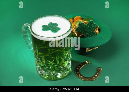 St. Patrick's Day Party. Grünes Bier, Kobold Hut mit Gold, Hufeisen und dekorativen Kleeblättern auf grünem Hintergrund Stockfoto