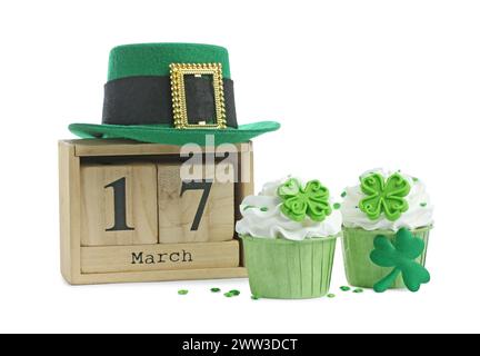 St. Patrick's Day, Party am 17. März. Leckere, festlich dekorierte Cupcakes, grüner Leprechaun Hut und Holzblock Kalender, isoliert auf weiß Stockfoto