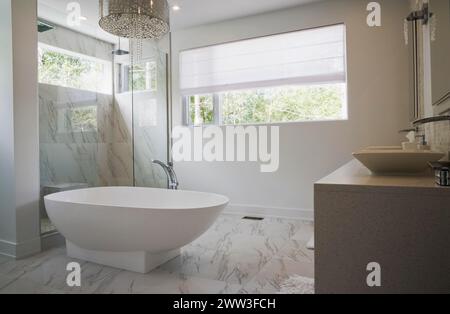 Glasdusche mit weißer freistehender Badewanne aus Acryl im Hauptbadezimmer mit Marmorfliesen im luxuriösen Haus, Quebec, Kanada Stockfoto