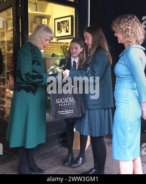 Königin Camilla wird von den Schwestern Matilda Brown, 16 (2. Rechts) und Dolly Brown, 13 von der Strathearn School, präsentiert, als sie nach einem Besuch in der Lisburn Road in Belfast verlässt, um Ladenbesitzer und Mitarbeiter zu treffen. und erfahren Sie mehr über ihren positiven Beitrag für die Gemeinde während ihres zweitägigen offiziellen Besuchs in Nordirland. Bilddatum: Donnerstag, 21. März 2024. Stockfoto