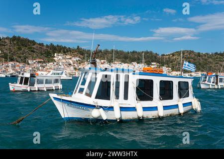 Ein kleines Boot schwingt auf dem klaren Wasser eines malerischen Hafens mit Blick auf die Stadt im Hintergrund, Wassertaxi, Blick von Galatas, Argolis, nach Poros Stockfoto