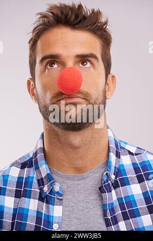 Clown, Nase und Mann denken mit lustigen, verrückten und komischen Ideen in einem Studio. Kostüm, schrullig und mit einem Mann mit Grau aufschauend Stockfoto