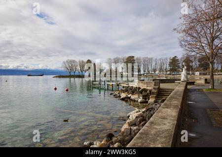 Blick auf den Genfer See mit Frachtschiff von der Uferpromenade mit der Statue der Jungfrau des Genfer Sees, Vierge du Lac im Stadtteil Ouchy Stockfoto