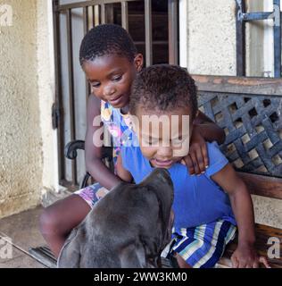 afrikanisches Mädchen und Junge spielen mit ihrem Boerboel-Welpen vor dem Haus Stockfoto