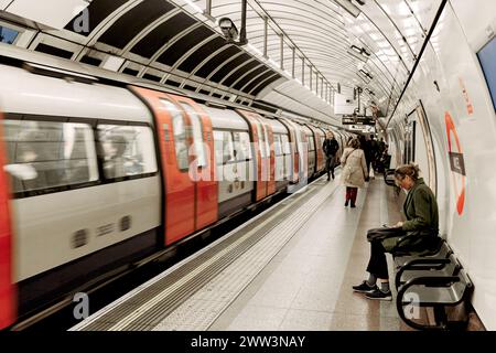 An der Angel U-Bahn-Station in London, wo Leute auf dem Bahnsteig laufen oder warten und ein Zug direkt vom Bahnhof abfährt. Stockfoto