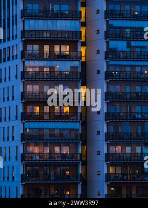 Ein hohes Gebäude mit zahlreichen Balkonen wird nachts beleuchtet und zeigt die leuchtenden Lichter in den Zimmern und auf den Balkonen. Das Archit Stockfoto