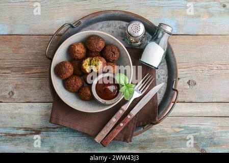Falafelteller mit Gewürz und Suppe auf Metalltablett auf hölzernem Hintergrund, Blick von oben Stockfoto