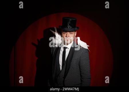 Eleganter, geheimnisvoller Illusionist, der Tricks mit Taube und Kaninchen zeigt Stockfoto