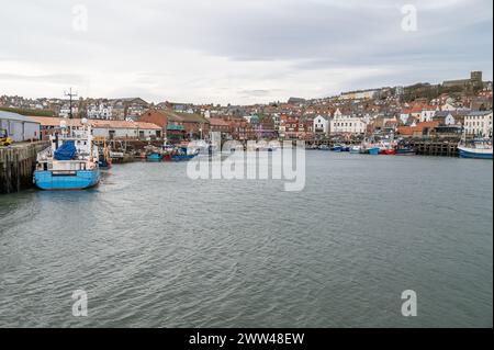 Kommerzielle Boote liegen im Hafen von Scarborough mit der Stadt dahinter in Yorkshire, England Stockfoto