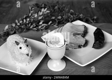 Traditionelle Gerichte zum Osterfrühstück und Butterlamm auf Holztisch in Polen, monochrom Stockfoto