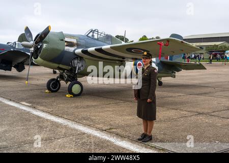Frau in WAF-Uniform steht neben einer Grumman FM2 Wildcat auf der Duxford Battle of Britain Air Show 2022, Duxford Airfield, Cambridgeshire, England, Großbritannien Stockfoto