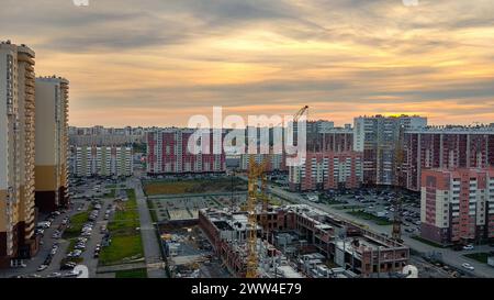 Blick von oben auf neue Gebäude und Wohngebäude vor dem Hintergrund des Sonnenuntergangs und des Abendhimmels Stockfoto