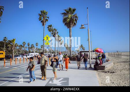 10. März 2024, Los Angeles, USA. Venedig Strand an einem hellen, sonnigen Tag. Menschenmassen Touristen Wanderweg entlang der Fußgängerzone des Broadwalk. Radfahrer fahren auf der Fahrradstraße. Wunderschöner Blick aufs Meer Stockfoto
