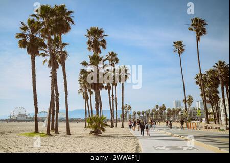 10. März 2024, Los Angeles, USA. Venedig Strand an einem hellen, sonnigen Tag. Menschenmassen Touristen Wanderweg entlang der Fußgängerzone des Broadwalk. Radfahrer fahren auf der Fahrradstraße. Wunderschöner Blick aufs Meer Stockfoto