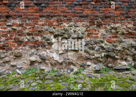 Detail der antiken Stadtmauer von London, Großbritannien. Eine mittelalterliche Mauer mit der römischen Festungsmauer an der Basis und gekrönt mit einer Backsteinbrüstung, die 1477 hinzugefügt wurde. Stockfoto