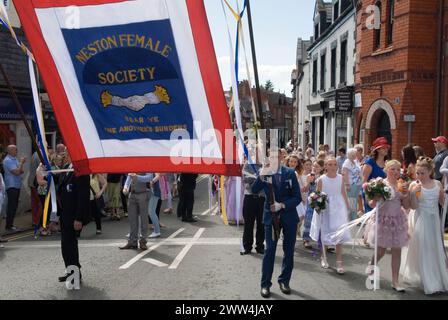 Neston Female Friendly Society Annual Club Walking Day. Frauen und Kinder – Mädchen ziehen durch das Dorf hinter dem Vereinsbanner „Neston Female Society Bären Sie sich gegenseitig die Lasten“. Neston Cheshire UK 2015. 2010er Jahre HOMER SYKES Stockfoto