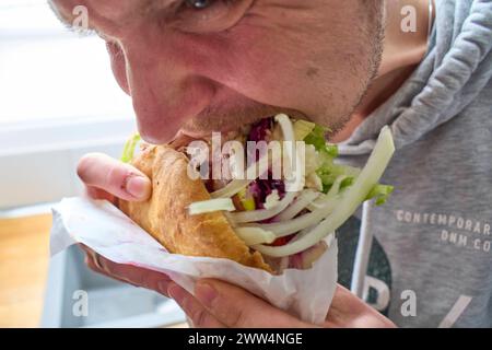Augsburg, Bayern, Deutschland - 21. März 2024: Ein junger Mann beißt hungrig in einen vegetarischen Döner Döner mit viel Salat *** ein junger Mann beißt hungrig in einem vegetarischen Döner Kebap mit viel Salat Stockfoto