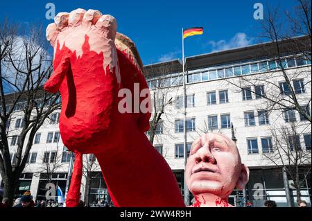 17.03.2024, Berlin, Deutschland, Europa - Tausende Menschen protestieren vor der russischen Botschaft unter den Linden im Berliner Bezirk Mitte unter dem Titel Schluss mit Putin, mit Krieg, Luege und Repressionen gegen den russischen Praesidenten Putin und gegen den Angriffskrieg auf die Ukraine, Wavend zeitgleich in Russland der letzte Tag der Praesidentschaftswahl stattfindet. In dieser Aufnahme nimmt Putin in der Nachbildung einer riesigen Pappmachefigur symbolisch ein Blutbad in einer Wanne in den Nationalfarben der Ukraine. Im Hintergrund weht die deutsche Flagge ueber der Bundesbehoerd Stockfoto