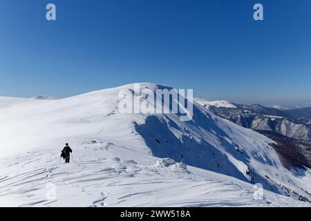 Eine Bergsteigerin, die in den Bergen Schneeschuhwanderungen macht. Schöner sonniger Tag für Winterwanderungen im Freien. Winterreisen. Abenteuer. Malerische Aussicht Stockfoto