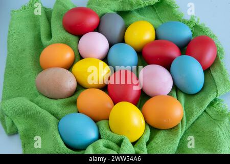 Eier in verschiedenen Farben, die Ostern feiern, auf grünem Stoffhintergrund Stockfoto
