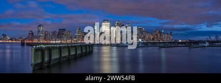 Panoramablick auf die Skyline von Manhattan über den Hudson River vom Walkway am Wasser in Jersey City bei Nacht Stockfoto