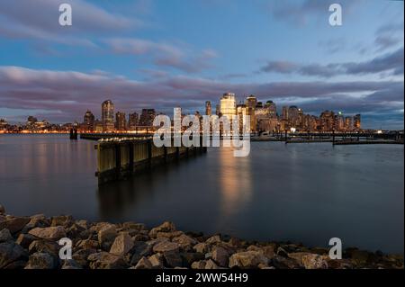 Blick auf die Skyline von Manhattan über den Hudson River vom Waterfront Walkway in Jersey City in der Abenddämmerung Stockfoto