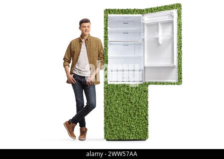 Junger Mann in kariertem Hemd und Jeans, der sich auf einen nachhaltigen Kühlschrank stützt, isoliert auf weißem Hintergrund Stockfoto