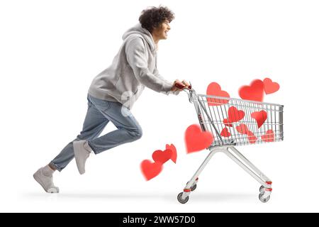 Junger Mann, der mit Herzen in einem Einkaufswagen läuft, isoliert auf weißem Hintergrund Stockfoto