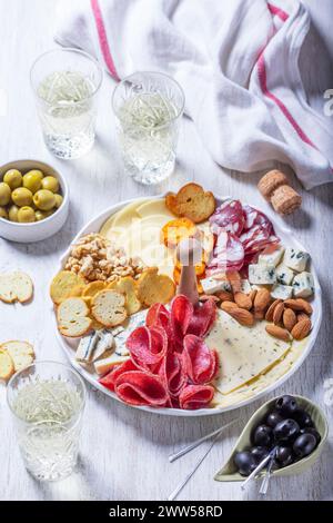 Aperitif, Champagner und Snack mit Wurst, Käse, Nüssen, Oliven und Crackern auf hellem Hintergrund. Stockfoto