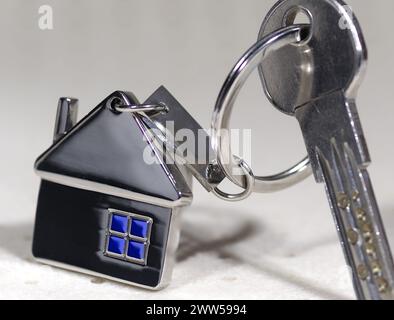 Haussymbol mit silbernen Schlüsseln auf abstraktem Hintergrund. Immobilienkonzept Stockfoto