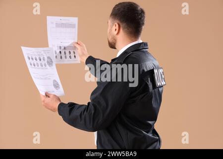 Männlicher Polizist mit Dokumenten auf beigefarbenem Hintergrund Stockfoto