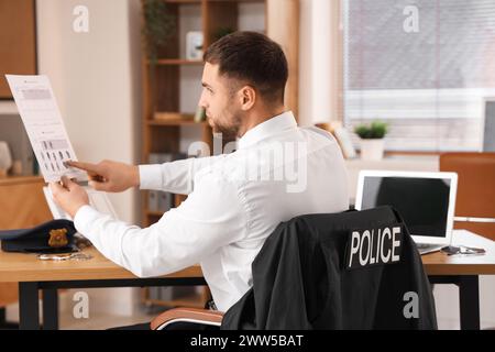 Männlicher Polizist mit Dokument im Amt Stockfoto