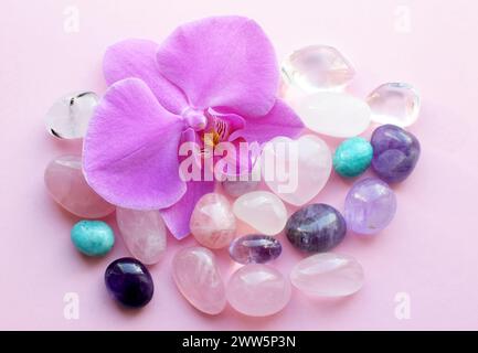 Wunderschöne Rosenquarzkristalle und Orchideenblume. Heilkristalle, die Magie der Edelsteine. Stockfoto