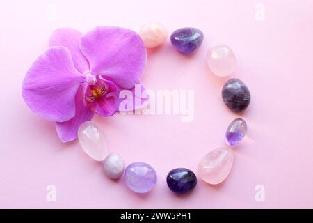 Amethyst-Kristalle, Rosenquarz und Orchideenblüte. Heilkristalle, die Magie der Edelsteine. Stockfoto