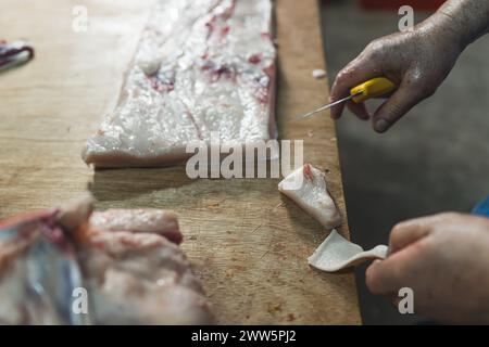 Nahaufnahme von Metzgerhänden, die rohe Steaks auf dem Metzgerblock schneiden. Hochwertige Fotos Stockfoto