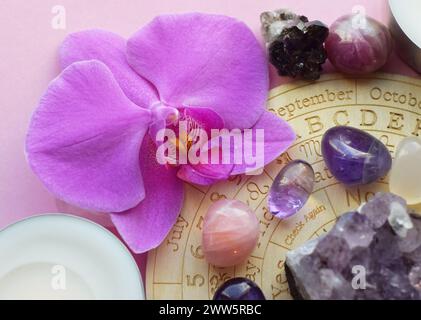 Amethyst-Kristalle, Rosenquarz und Orchideenblüte. Heilkristalle, die Magie der Edelsteine. Stockfoto