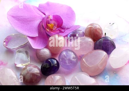 Amethyst-Kristalle, Rosenquarz und Orchideenblüte. Heilkristalle, die Magie der Edelsteine. Stockfoto