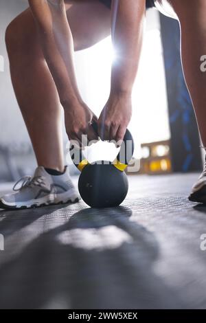 Eine junge kaukasische Frau greift im Fitnessstudio eine Kettlebell Stockfoto