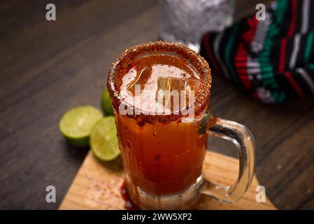 Michelada, typisch mexikanischer Cocktail auf einem Holztisch. Bier-Cocktail. Stockfoto