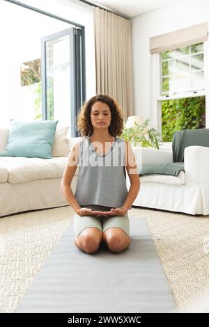 Eine junge kaukasische Frau meditiert während sie zu Hause Yoga macht Stockfoto