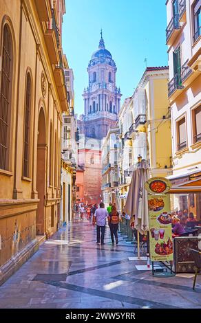 MALAGA, SPANIEN - 28. SEPTEMBER 2019: Die enge Calle San Agustin mit Restaurants im Freien und Blick auf die Kathedrale von Malaga, am 28. September in Malaga Stockfoto