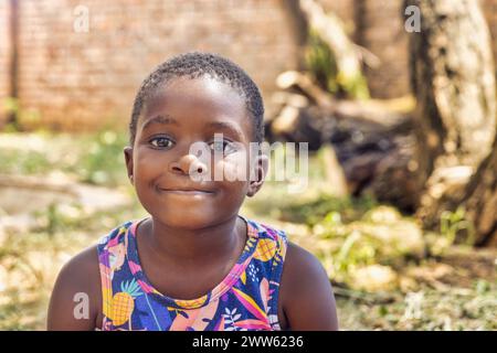 Lächelndes afroamerikanisches Mädchen, das draußen im Garten steht Stockfoto