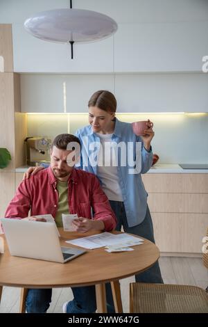Ernsthafte verheiratete Paare berechnen sorgfältig Ausgaben und Budget am Küchentisch mit Laptop. Stockfoto