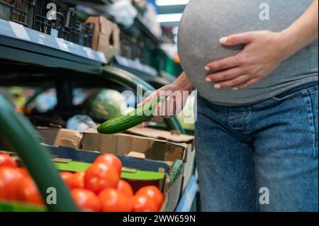 Schwangere kauft Gurken im Laden. Stockfoto