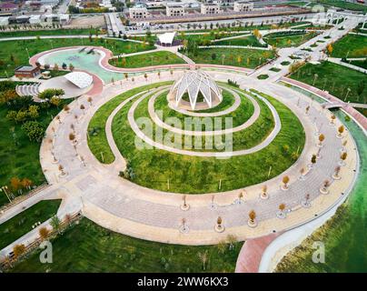 Luftdrohnenaufnahme von Gazebo mit blumenförmigem Dach im Park und spiralförmigem Pfad herum. Verbesserung des Zhibek ZHoly Kunstparks in Turkestan, Kasachst Stockfoto