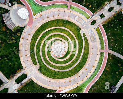 Luftdrohnenaufnahme von Gazebo mit blumenförmigem Dach im Park und spiralförmigem Pfad herum. Verbesserung des Zhibek ZHoly Kunstparks in Turkestan, Kasachst Stockfoto