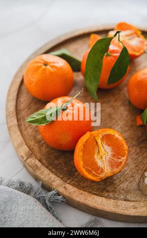 Mandarinen mit grünen Blättern auf Holztablett Stockfoto