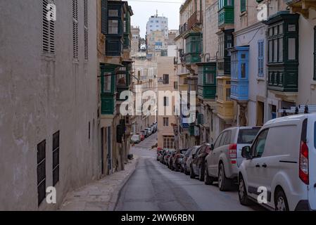 Eine verlassene Gasse mit einer Reihe von geparkten Fahrzeugen, einschließlich Autos und Lieferwagen, die in einer Reihe auf beiden Seiten der Straße angeordnet sind Stockfoto